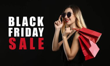 Koyu arkaplanda alışveriş torbaları olan güzel bir genç kadın. Kara Cuma indirimi