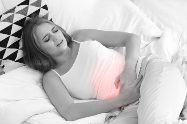Genç kadın yatakta karın ağrısı muzdarip