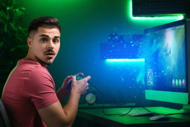 Şaşırmış genç adam kulüpte bilgisayar oyunu oynamak