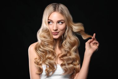 Siyah arka planda güzel kıvırcık saçlı genç bir kadın.