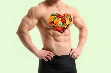 Renk arka plan karşı göğsünde boyalı sebzeler ile Kas vücut geliştirmeci
