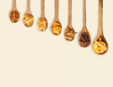 Tahta kaşıklar ışık arka plan üzerinde pişmemiş makarna ile