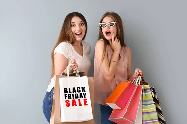 Gyönyörű fiatal nők bevásárló táskák, szürke háttér. Fekete péntek eladó — Stock Fotó