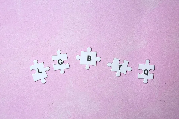 Puzzle pieces with abbreviation LGBTQ on color background — Stock Photo, Image