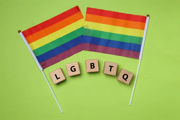 Cubos de madera con abreviatura LGBTQ y banderas de arco iris sobre fondo de color —  Fotos de Stock