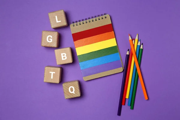 Wooden cubes with abbreviation LGBTQ and stationery on color background — Stock Photo, Image