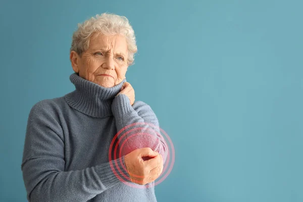 Seniorin leidet unter Schmerzen im Ellbogen auf farbigem Hintergrund — Stockfoto