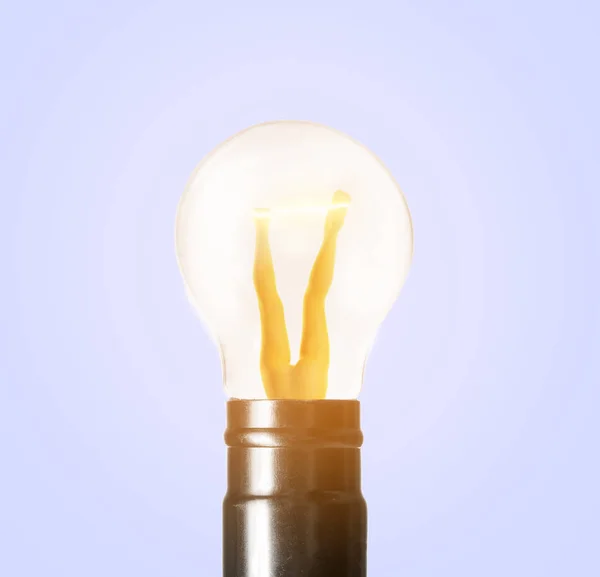 Long female legs inside glowing light bulb on grey background