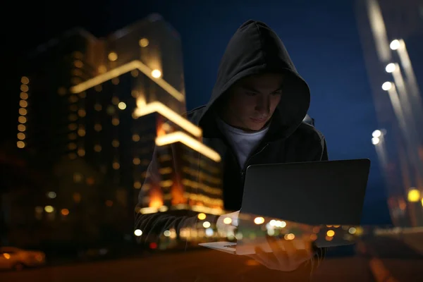 Dupla exposição de hacker profissional com laptop e cidade à noite — Fotografia de Stock