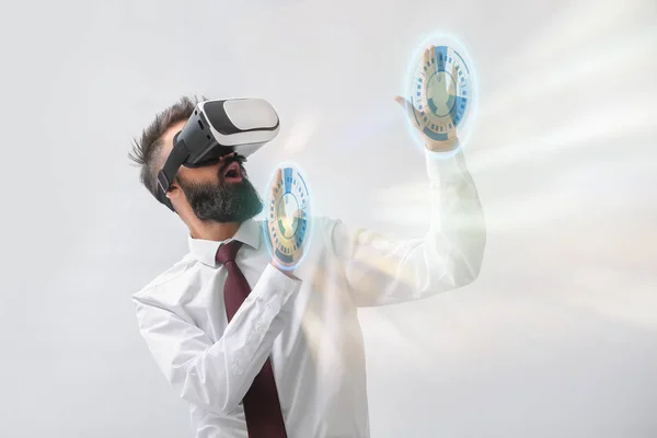 Geschäftsmann trägt VR-Brille und nutzt virtuellen Bildschirm auf hellem Hintergrund — Stockfoto