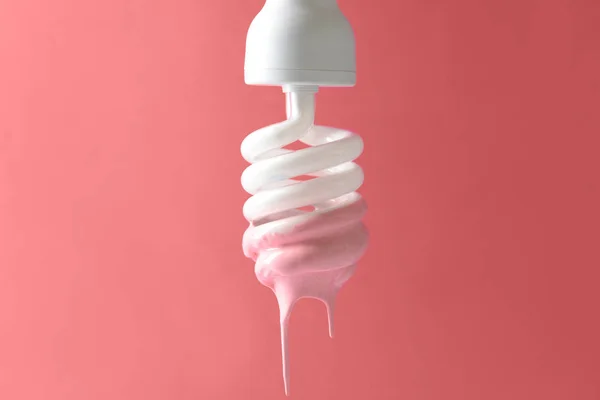 Paint dripping from light bulb on coral background