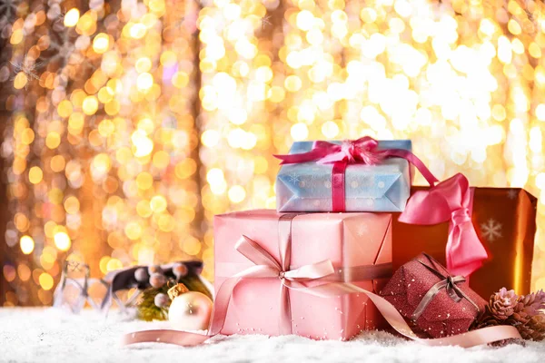 Many Christmas gift boxes on snow against blurred lights — Stock Photo, Image