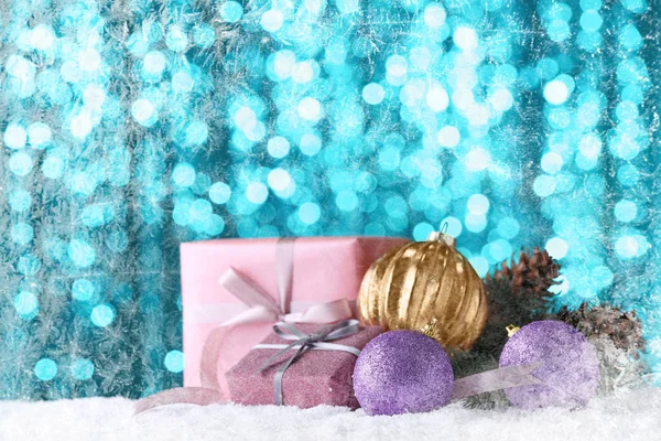 Різдвяні подарунки та прикраси на снігу проти розмитих вогнів — стокове фото