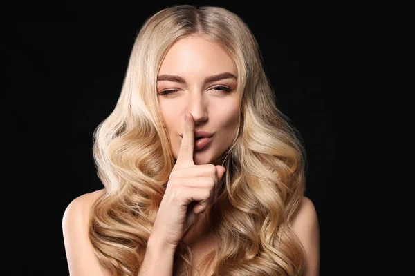 Jeune femme aux beaux cheveux bouclés montrant un geste de silence sur fond sombre — Photo