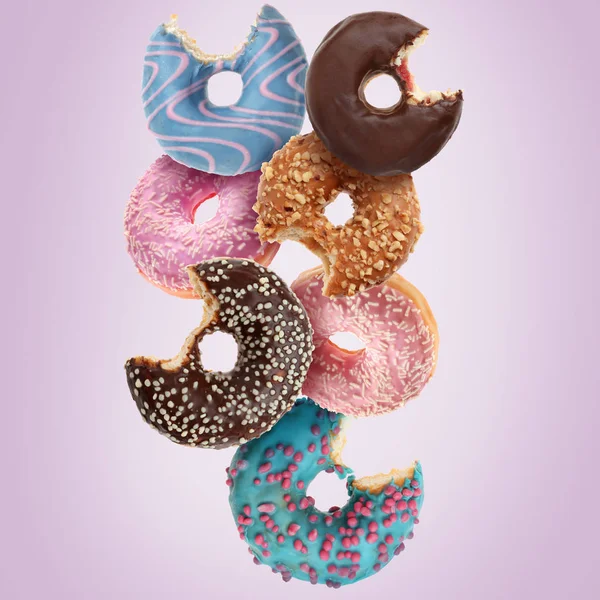 Many different bitten donuts on color background