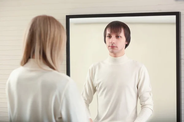 Jonge vrouw die naar haar imaginaire reflectie in spiegel kijkt. Concept van transgenderisme — Stockfoto