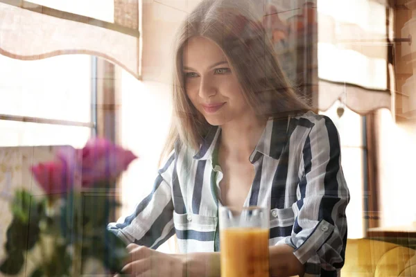 Junge Frau mit Laptop bei der Arbeit im Café, Blick durch Fenster — Stockfoto