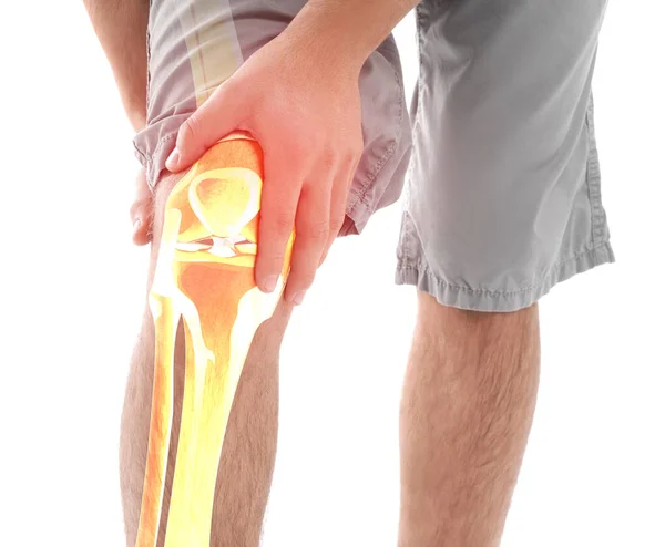 Jeune homme souffrant de douleur au genou sur fond blanc — Photo