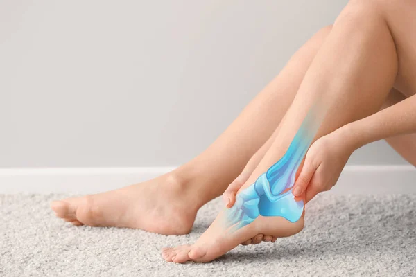 Mulher sofrendo de dor na perna enquanto sentado no tapete — Fotografia de Stock