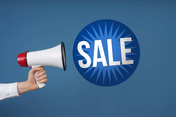 Female hand with megaphone and text SALE on blue background — Stock Photo, Image