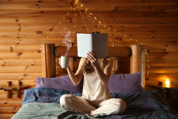 Hermosa mujer leyendo libro y tomando café en la mañana en el resort de invierno — Foto de Stock