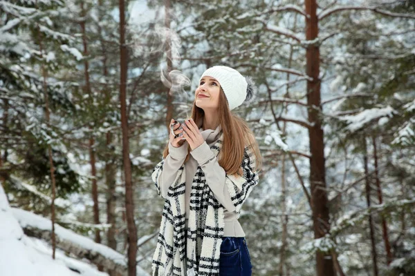 Vacker kvinna med varm dryck i vinter skog — Stockfoto