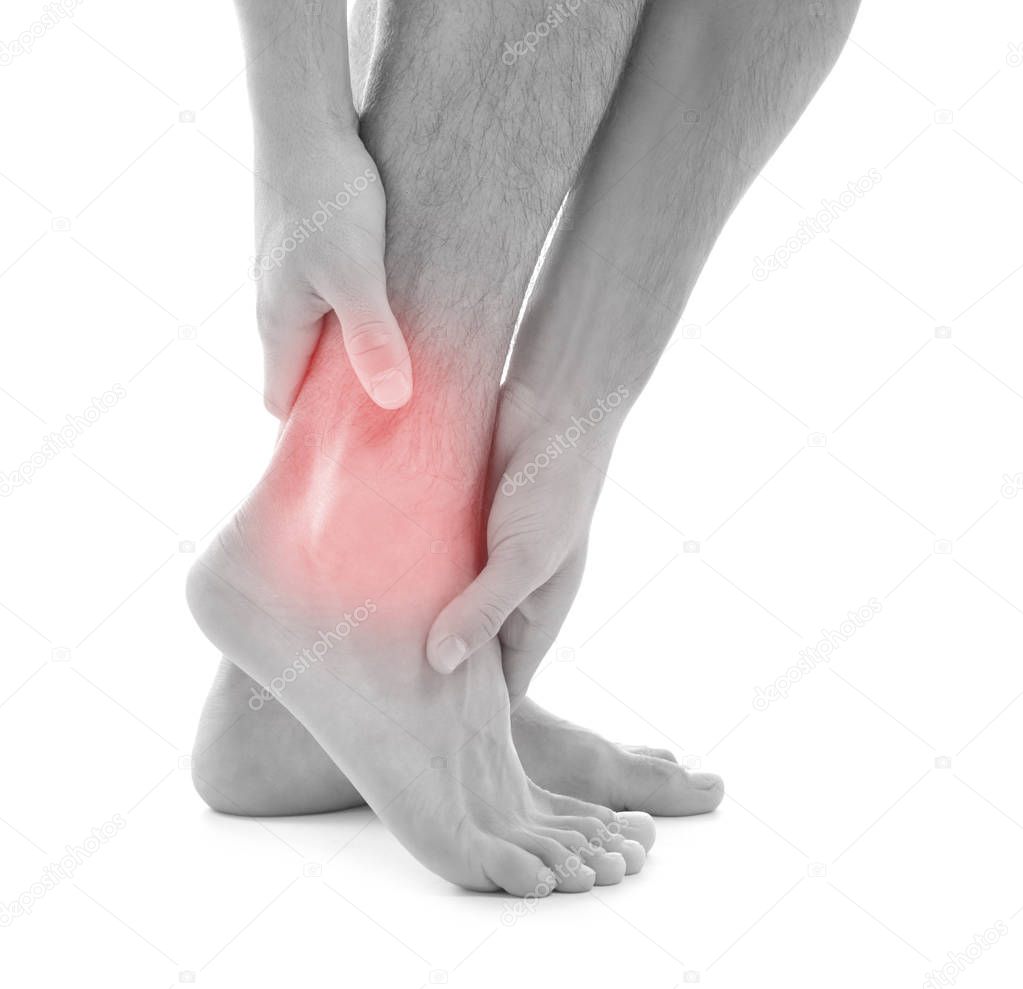 Young man suffering from pain in ankle on white background