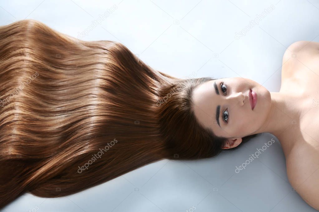 Young woman with beautiful hair on light background