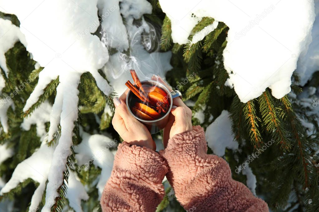 Woman with cup of hot mulled wine outdoors