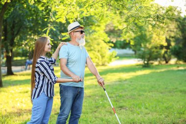 Blind mature man with daughter walking in park clipart