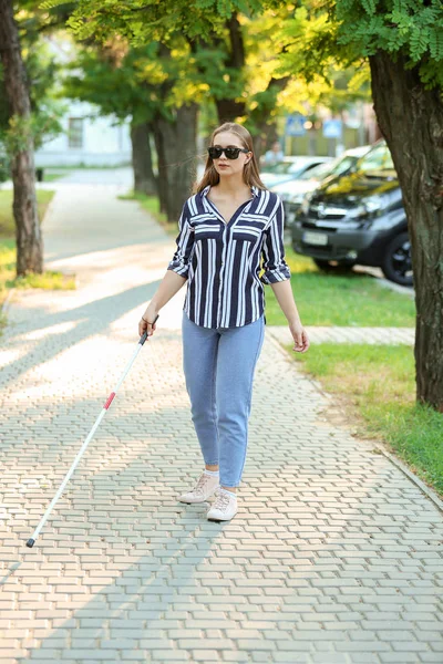 Young blind woman walking in park