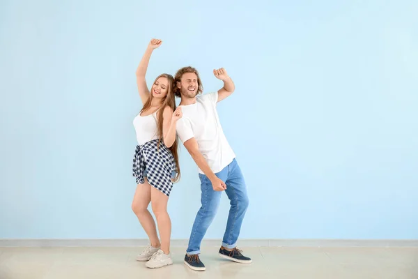 Cool pareja joven bailando contra la pared de color — Foto de Stock