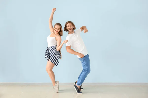 Cool young couple dancing against color wall — Stock Photo, Image