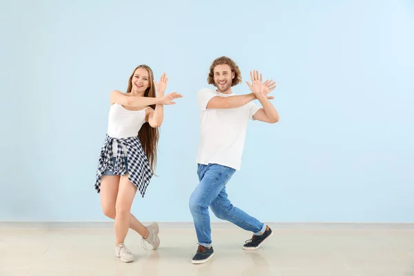 Cool pareja joven bailando contra la pared de color — Foto de Stock