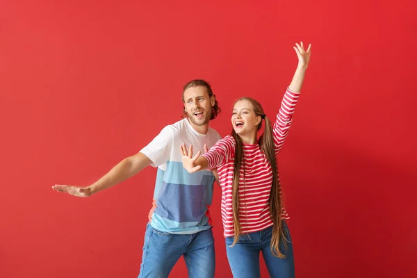 Cool mladý pár tanec proti barevnému pozadí — Stock fotografie