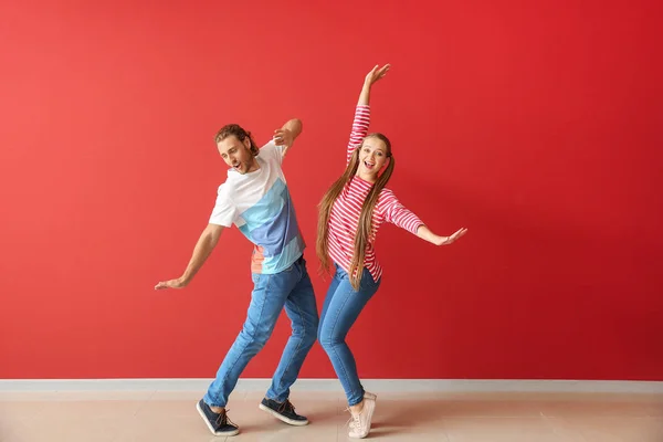 Cool pareja joven bailando contra la pared de color — Foto de Stock