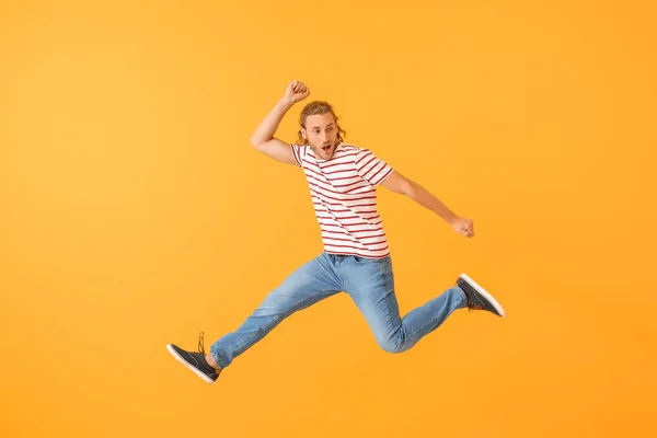 Jumping young man against color background — Stock Photo, Image