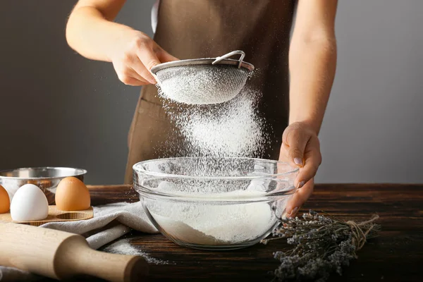 Woman sieving flour in kitchen — Stock Photo, Image