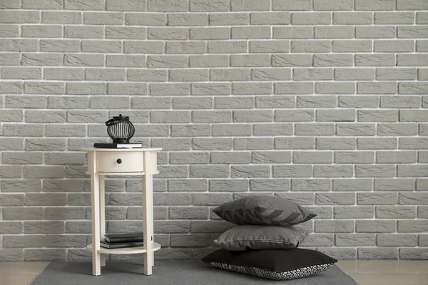 Odada gri tuğla duvara yakın masa ile Yumuşak yastıklar — Stok fotoğraf