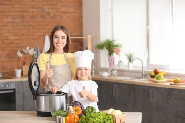 Kadın ve küçük kızı mutfakta modern çoklu ocak kullanarak