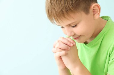 Renkli arka planda dua eden küçük çocuk