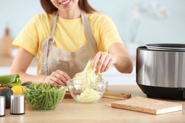 Genç bir kadın mutfakta yemek pişiriyor.