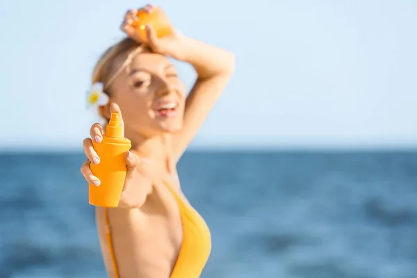 Beautiful young woman with sun protection cream on sea beach — Stock Photo, Image