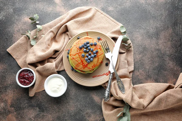 Plate with green pancakes, berry jam and sauce on grey background — Stock Photo, Image