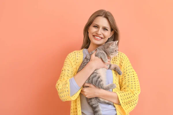 Beautiful young woman with cute cat on color background — Stock Photo, Image