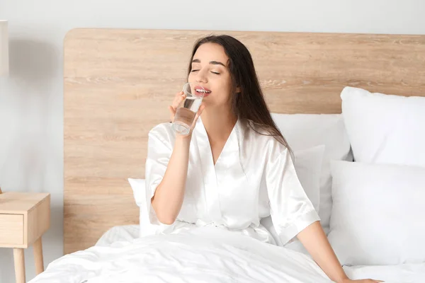 Morning of beautiful young woman drinking water in bedroom — Stock Photo, Image