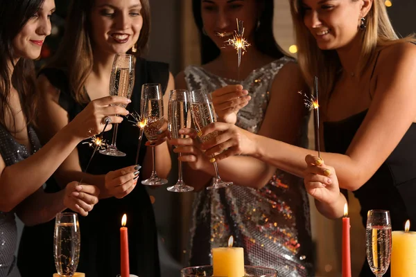 Happy women with Christmas sparklers and glasses of champagne at party — Stock Photo, Image