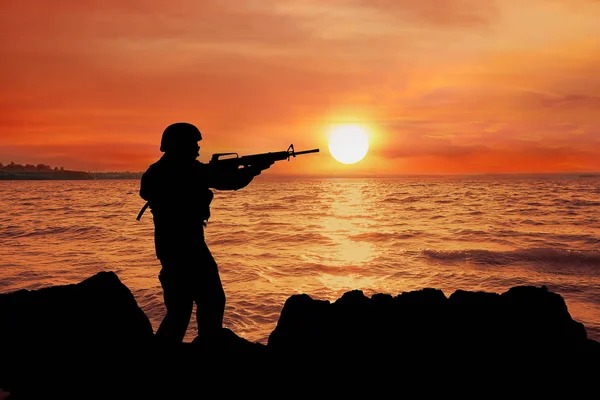 Silhouette of soldier in camouflage taking aim in river — Stock Photo, Image