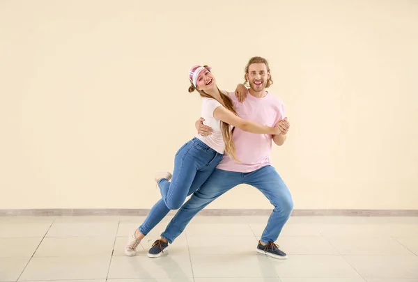 Cool young couple dancing against light wall — Stock Photo, Image