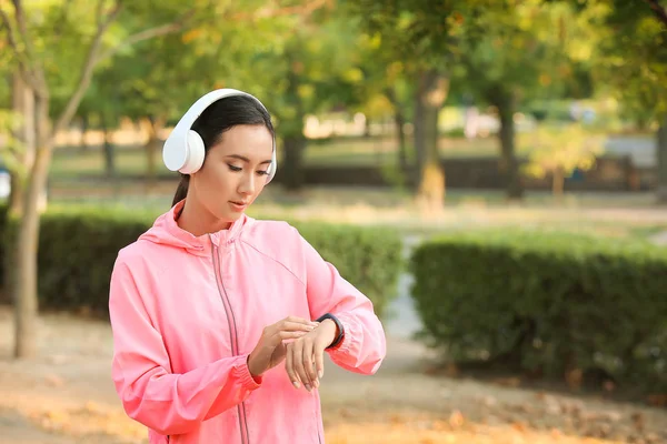 Sporty Asian woman with fitness tracker outdoors — Stock Photo, Image